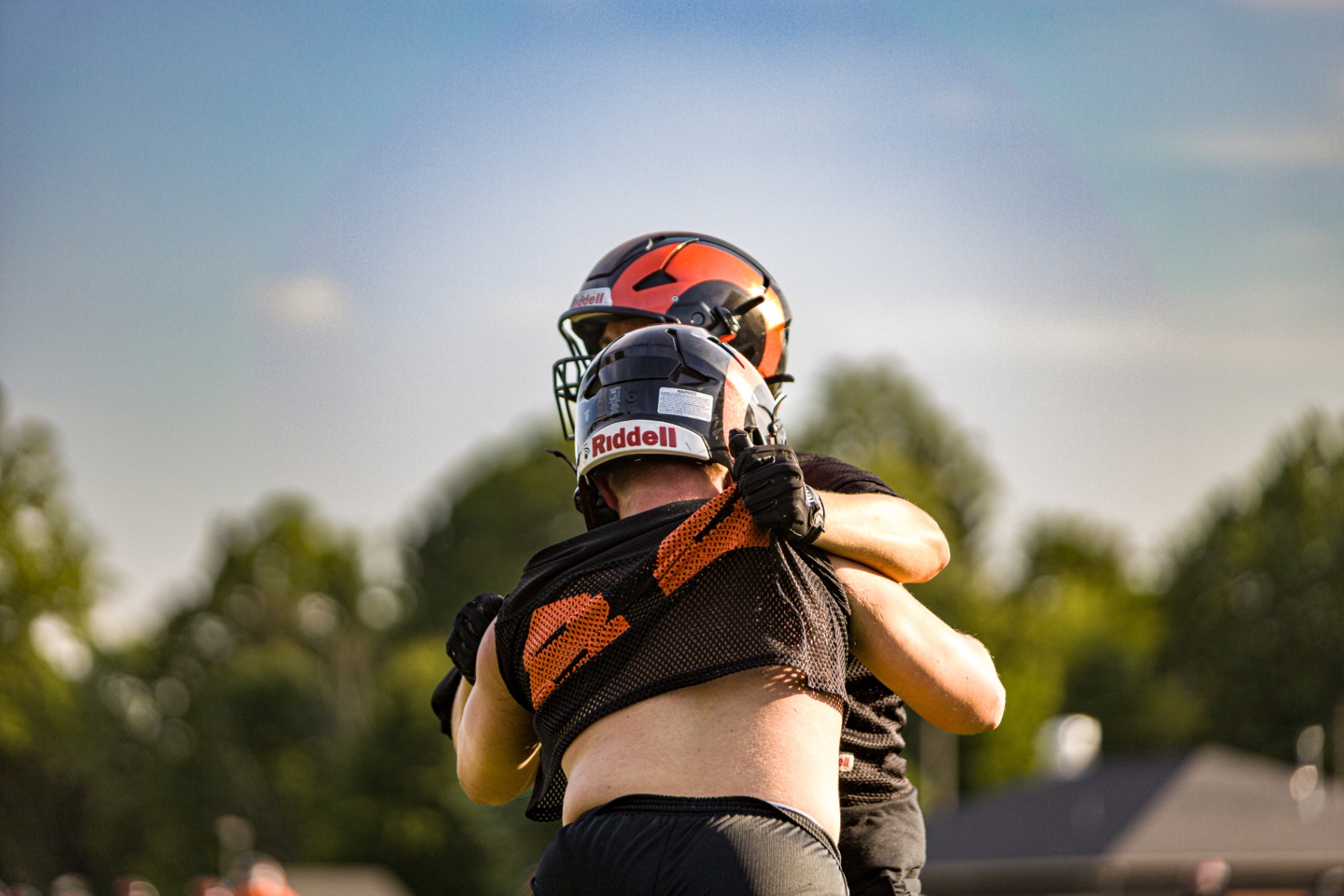 High school football teammates celebrating after a play — action photography by Striide