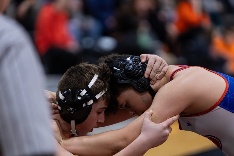 High school football players tangled after the whistle — sports photography by Striide